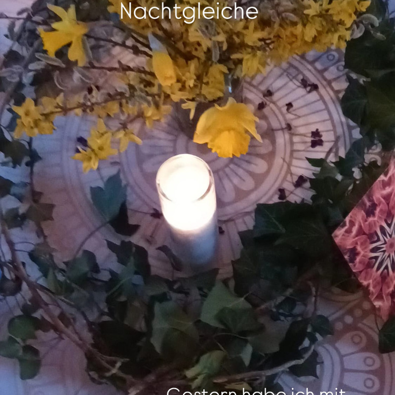 Blumengesteck mit weißer Kerze und Dekoration, beschriftet mit „Nachtgleiche“