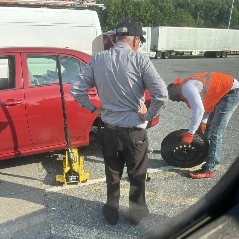 AMMO replacing tire on red car