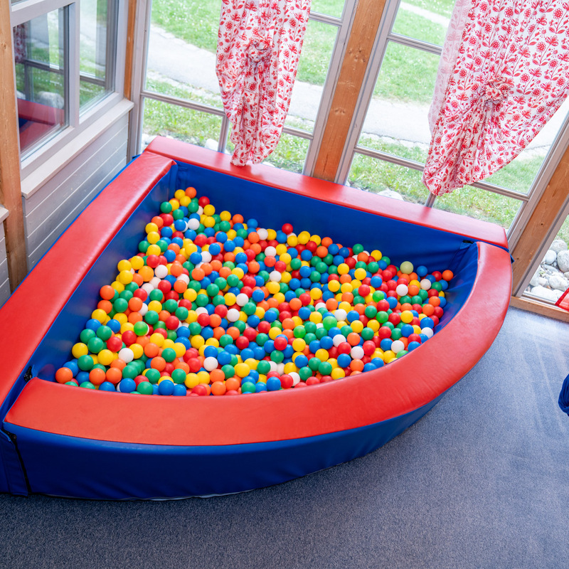 Bällebad in einer hellen Spielecke mit großen Fenstern