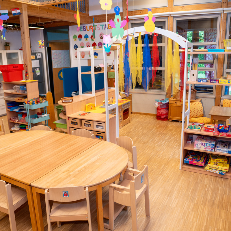 Bastel- und Spielebereich im Kindergarten mit Holztischen und Regalen