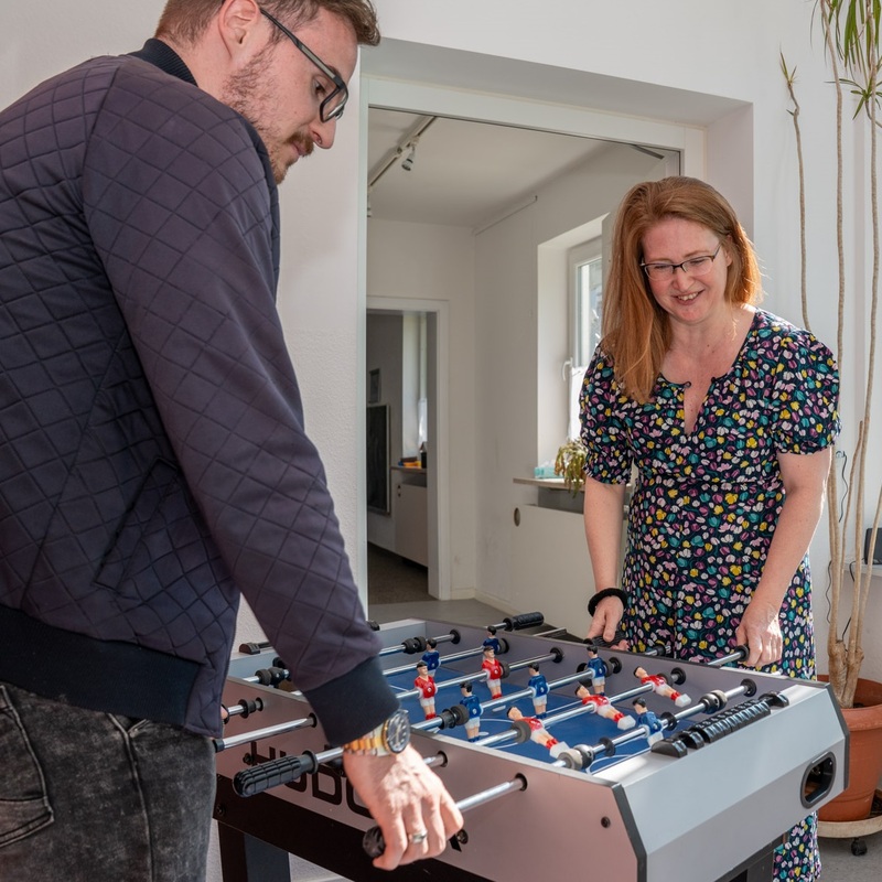 Zwei Erwachsene spielen an einem Tischkicker