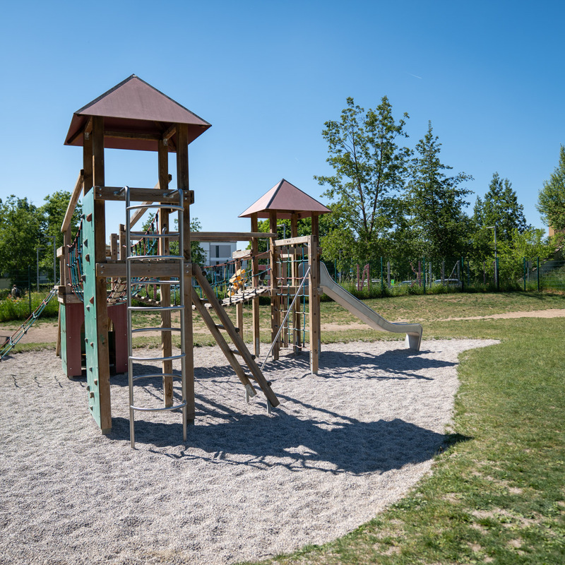 Außenspielplatz mit Klettergerüst, Rutsche und Schaukeln bei Sonnenschein