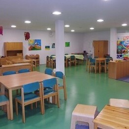 Großer Ess- und Aufenthaltsraum mit Holztischen und bunten Wänden