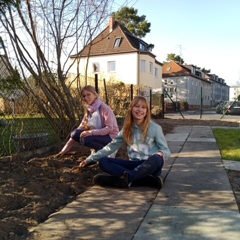 Stina und Alena helfen beim Anpflanzen der heimischen Wildhecke im Schulgarten