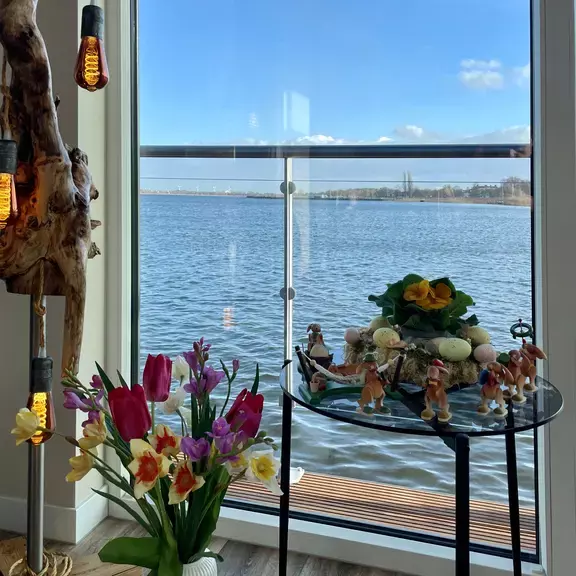 Osterdeko und Blumen am Fenster mit Wasserblick