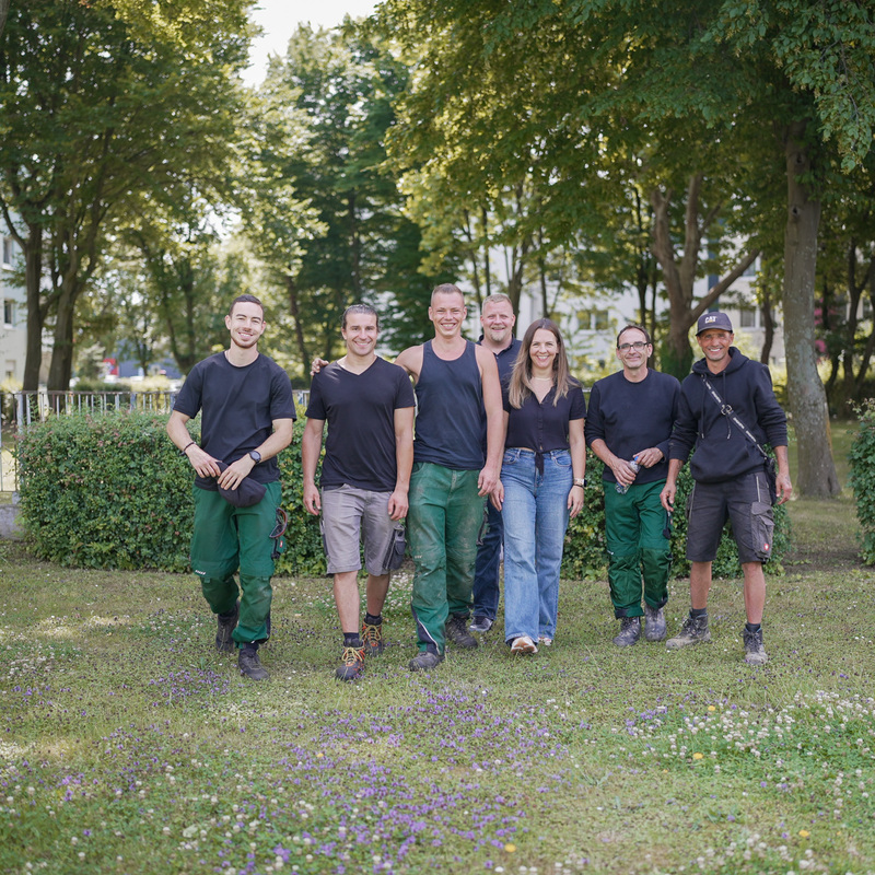 Teamfoto vor Bagger und Firmenfahrzeug