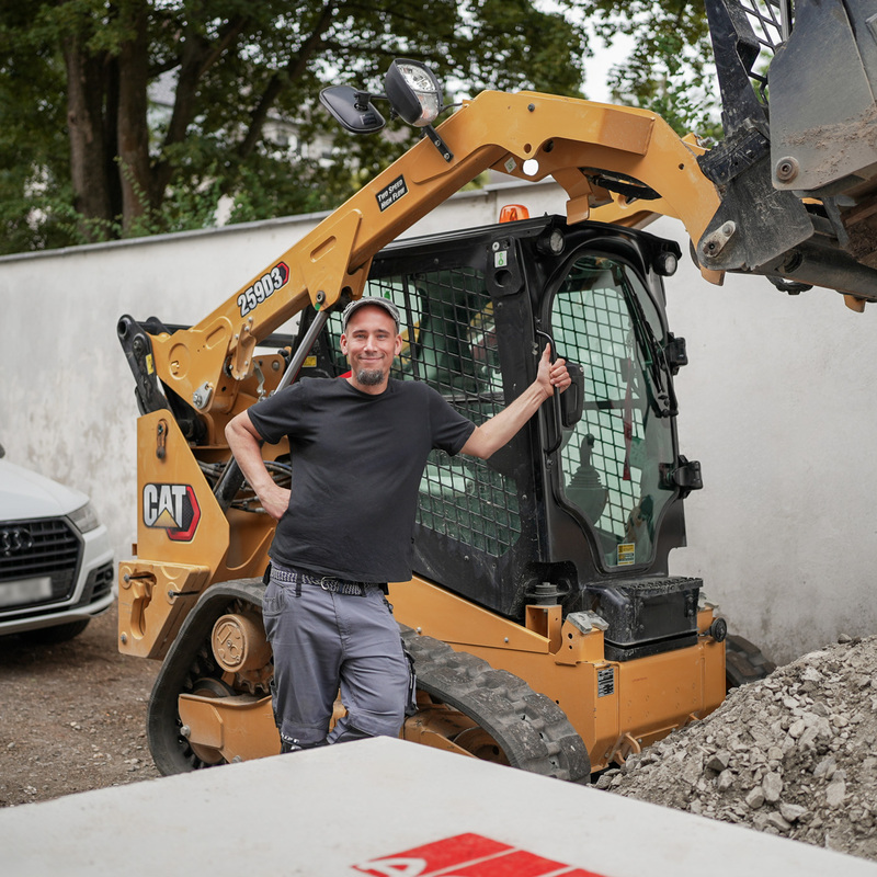 Arbeiter mit Trennschleifer in tiefer Baugrube