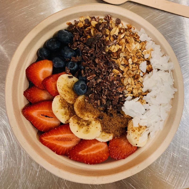 A bowl with strawberries, bananas, granola, blueberries and shredded coconut