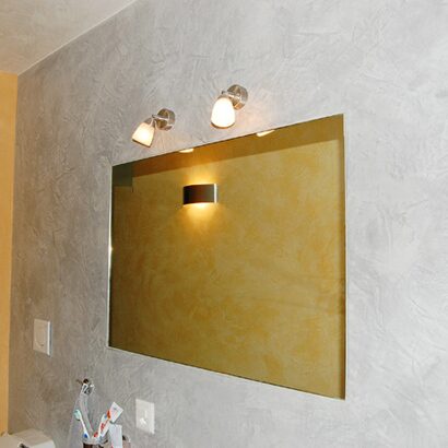 Graue Wand mit Spiegel und gelber Lichtreflexion