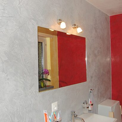 Bad mit grauer Spachtelwand und roter Akzentfläche