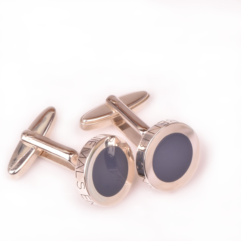 Zwei Paar roségoldene Manschettenknöpfe mit schwarzen Elementen auf weißem Hintergrund