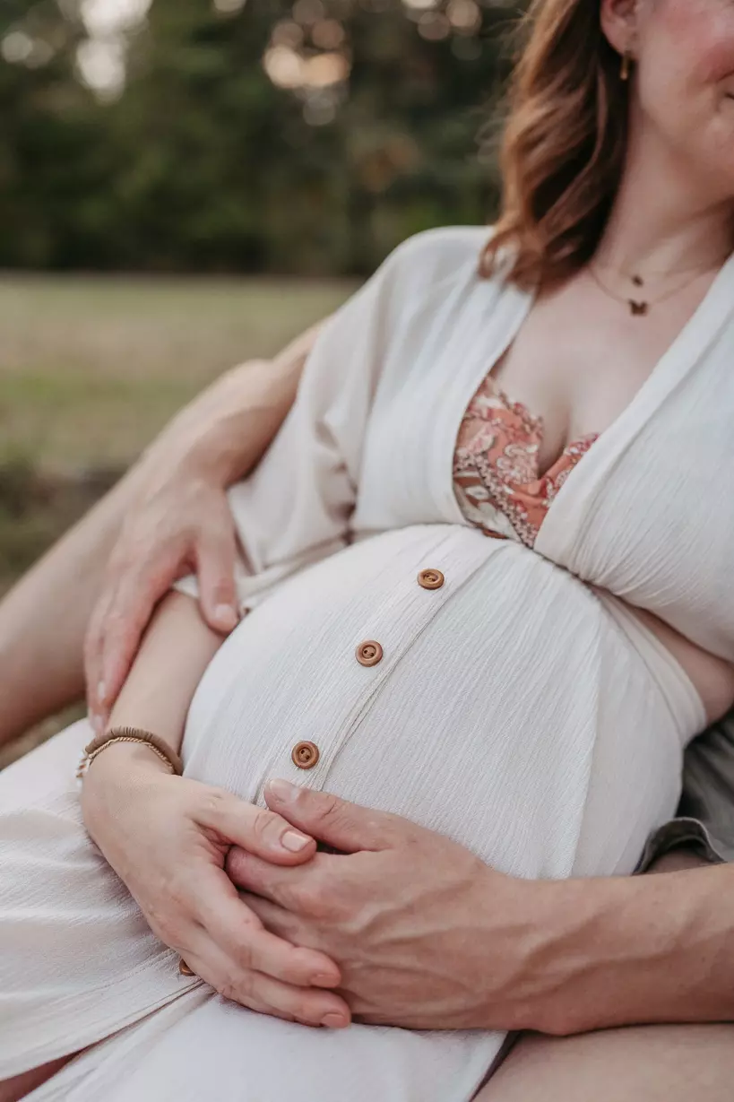 Ein Babybauch Fotoshooting in Berlin und Brandenburg. Der Vater hält liebevoll den Babybauch seiner Frau. 