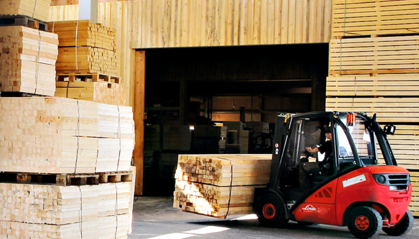 Gabelstapler steht vor großen Stapel mit Kanthölzern