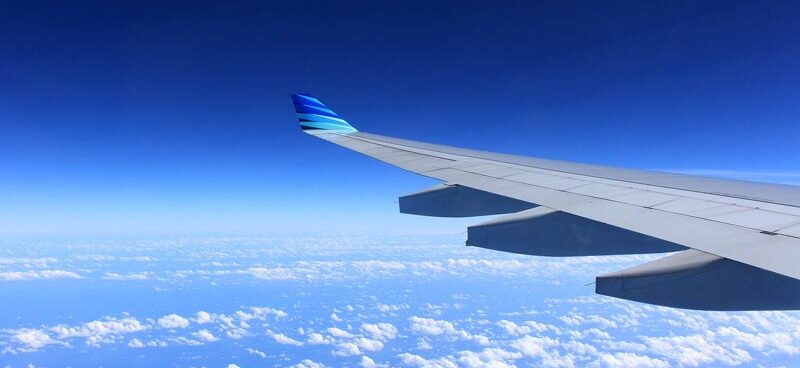 Foto aus einem Flugzeug heraus, man sieht Wolken und den Flügel