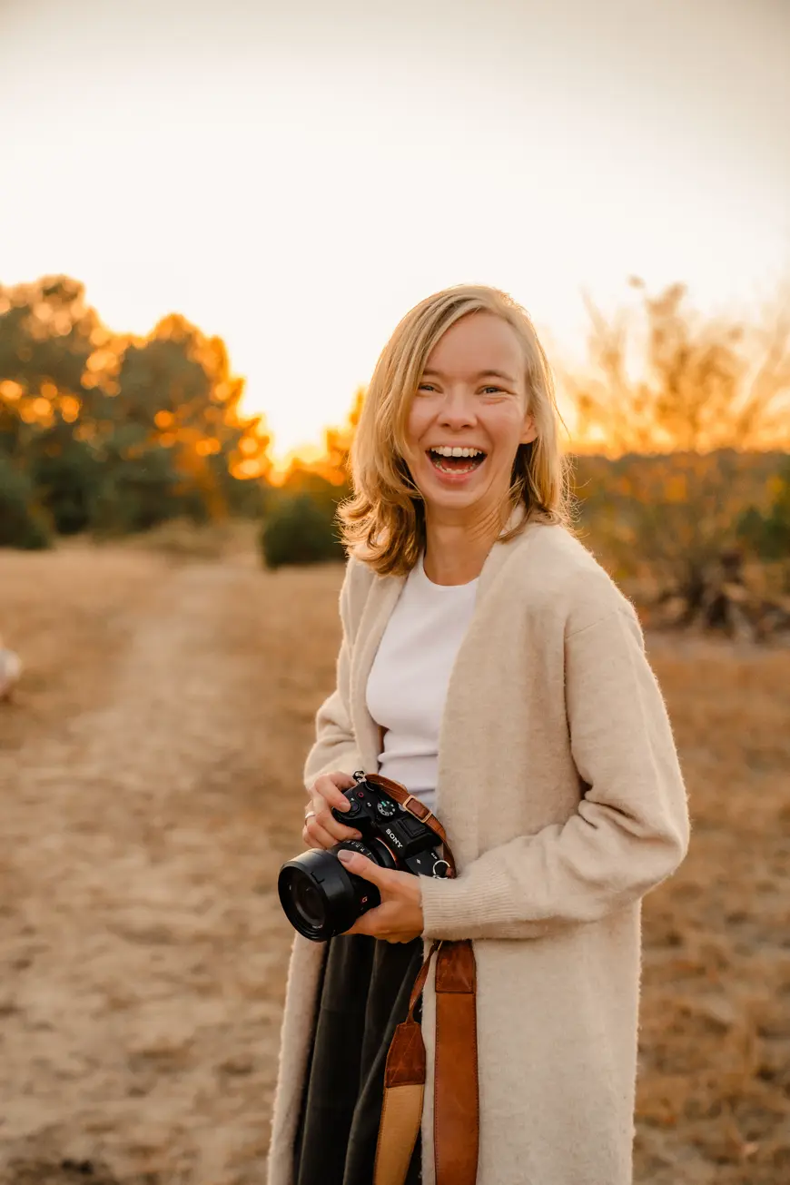 Die Fotografin Lisa Hambsch mit einer Kamera in der Hand. Sie ist Familienfotografin und Hochzeitsfotografin in Berlin