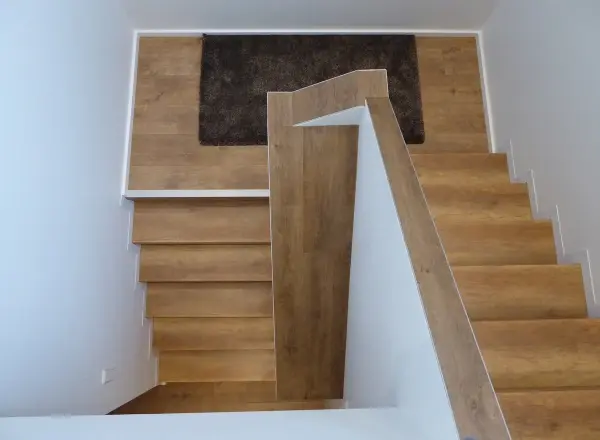 Renovierte Wendeltreppe von oben mit hellem Laminat in Eichenoptik und weißem Metallgeländer – Treppenrenovierung im Rhein-Main-Gebiet