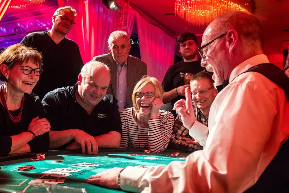 Lachende Gäste mit Croupier am Black-Jack-Tisch – Casino-Event mieten für unvergessliche Abende