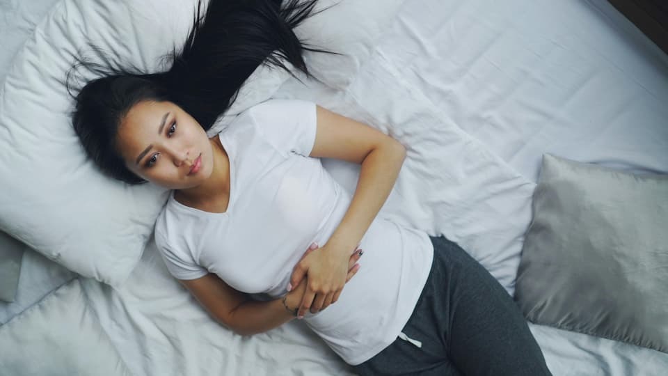 Frau mir Morbus Crohn hält sich den Bauch- Hypnose kann helfen Morbus Crohn zu  Überwinden