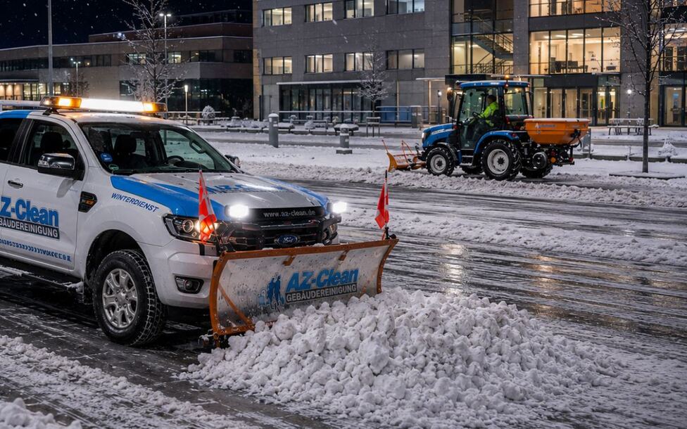 Räumfahrzeug von AZ-Clean mit Schneeschild und Traktor beim Winterdienst vor einem Bürogebäude